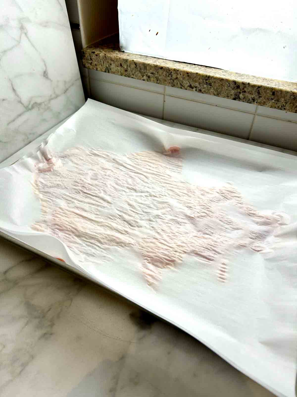 parchment paper placed on top of turkey skin.