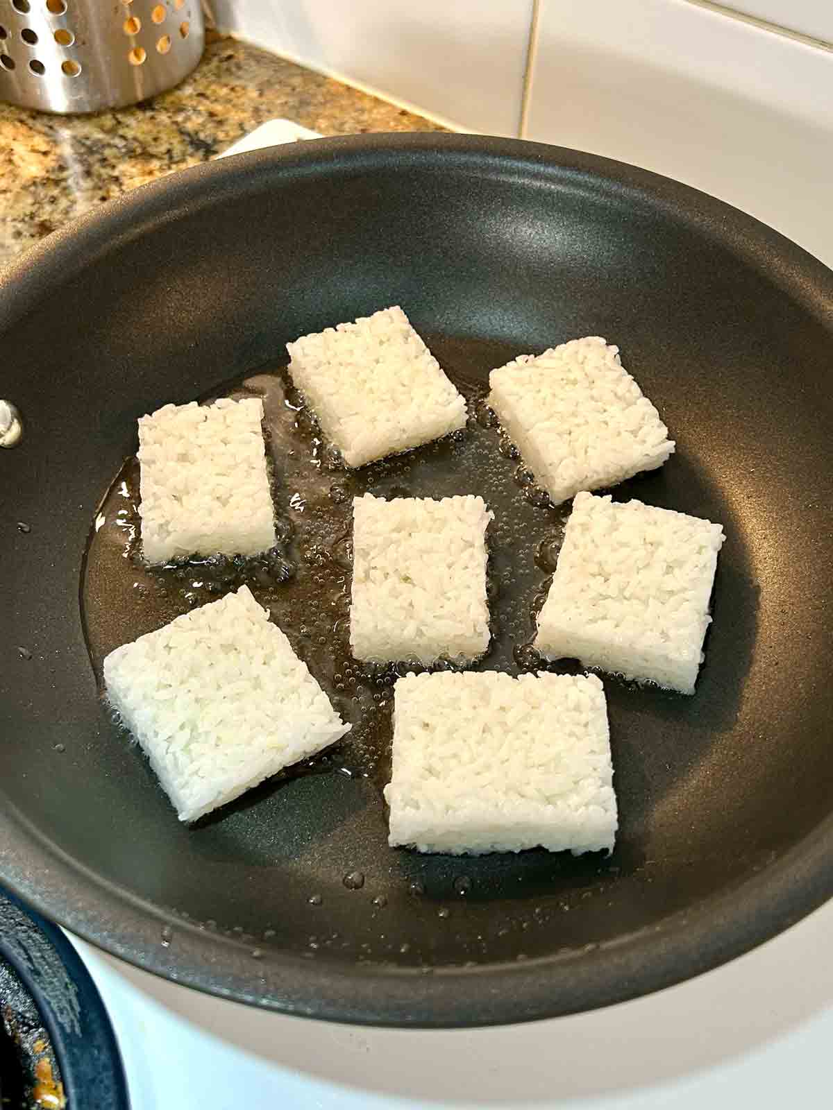 rice rectangles being pan-fried.