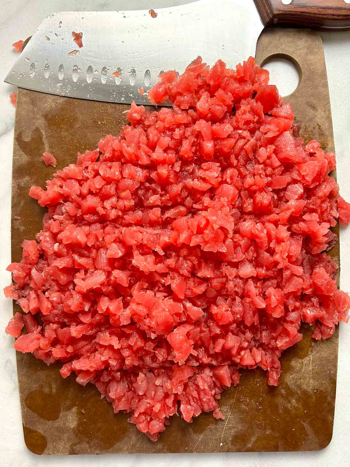 raw tuna finely minced on cutting board.