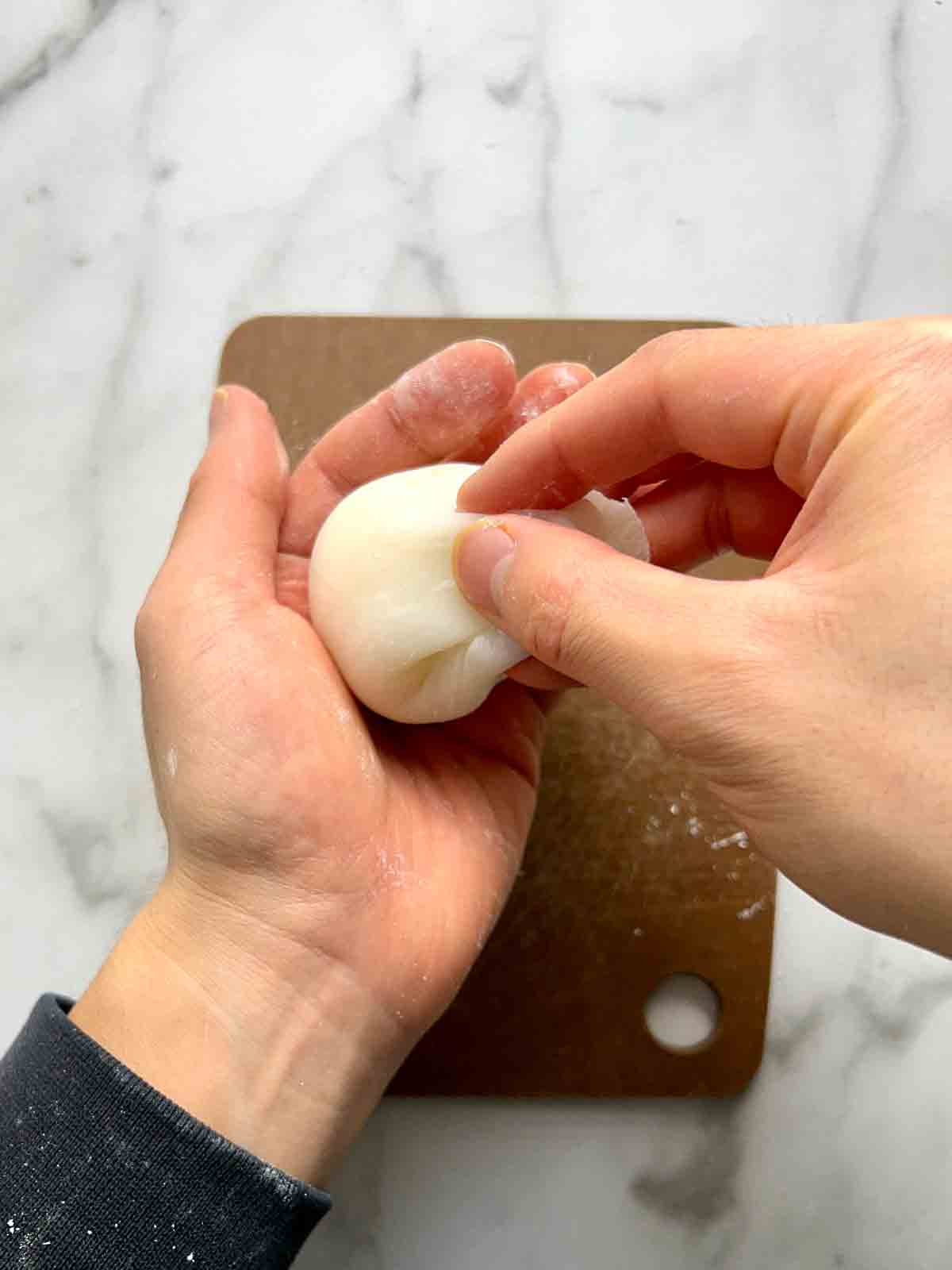 pulling up sides of mochi around filling.