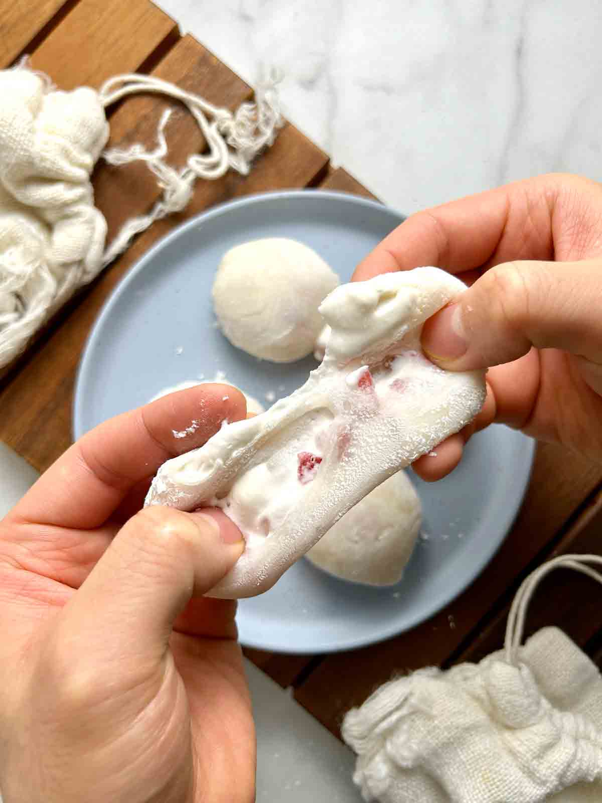 strawberry mochi being torn apart to show filling on the inside.