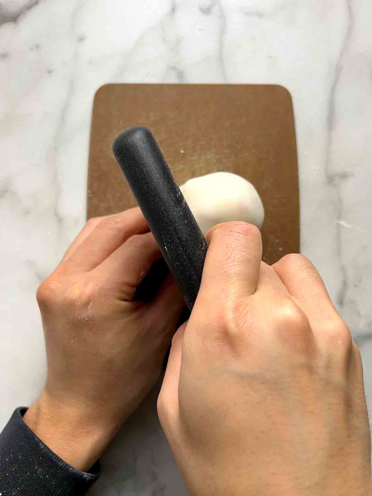 excess dough being chopped off mochi.