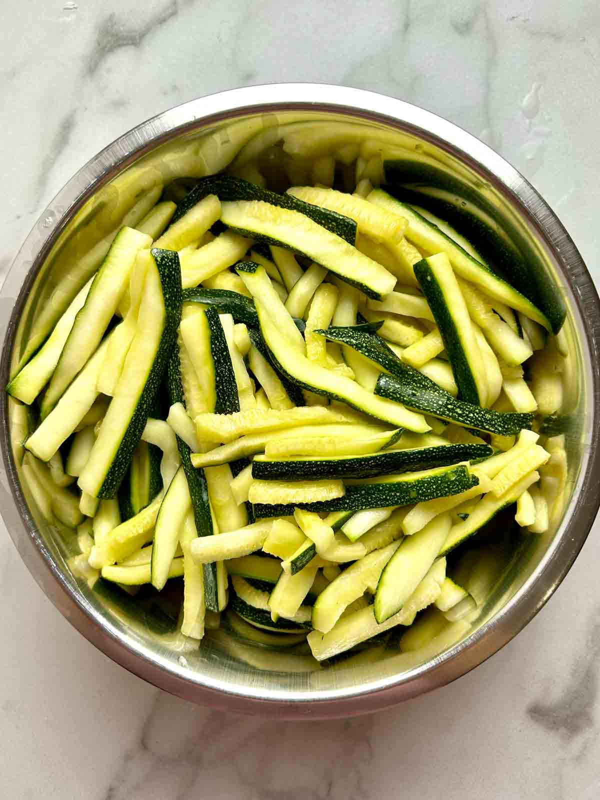 bowl of zucchini matchsticks that have been salted and squeezed dry.