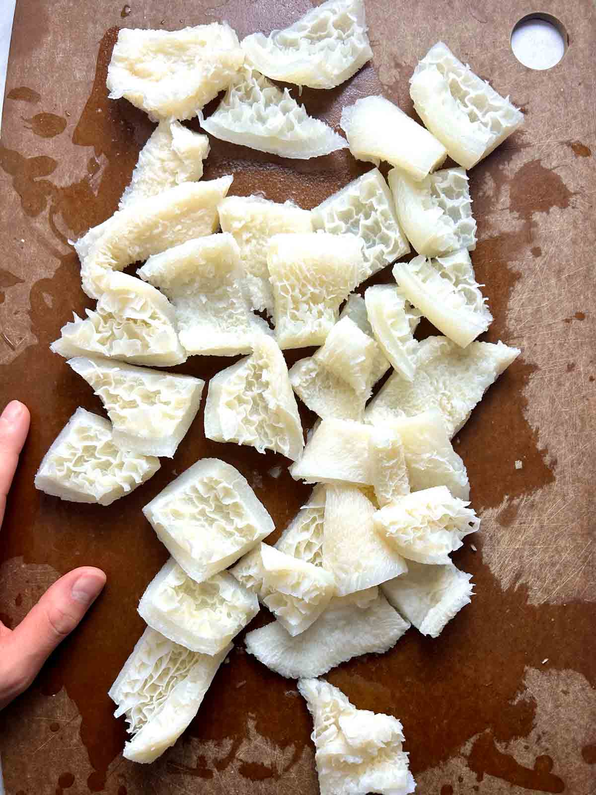 beef tripe cut into small chunks on cutting board.