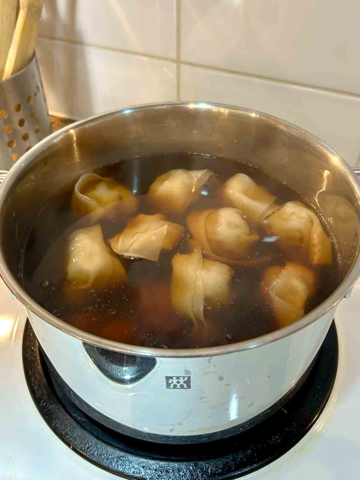 wontons rising to surface of boiling soup.