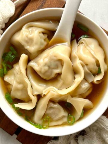 bowl of wonton soup garnished with scallions.