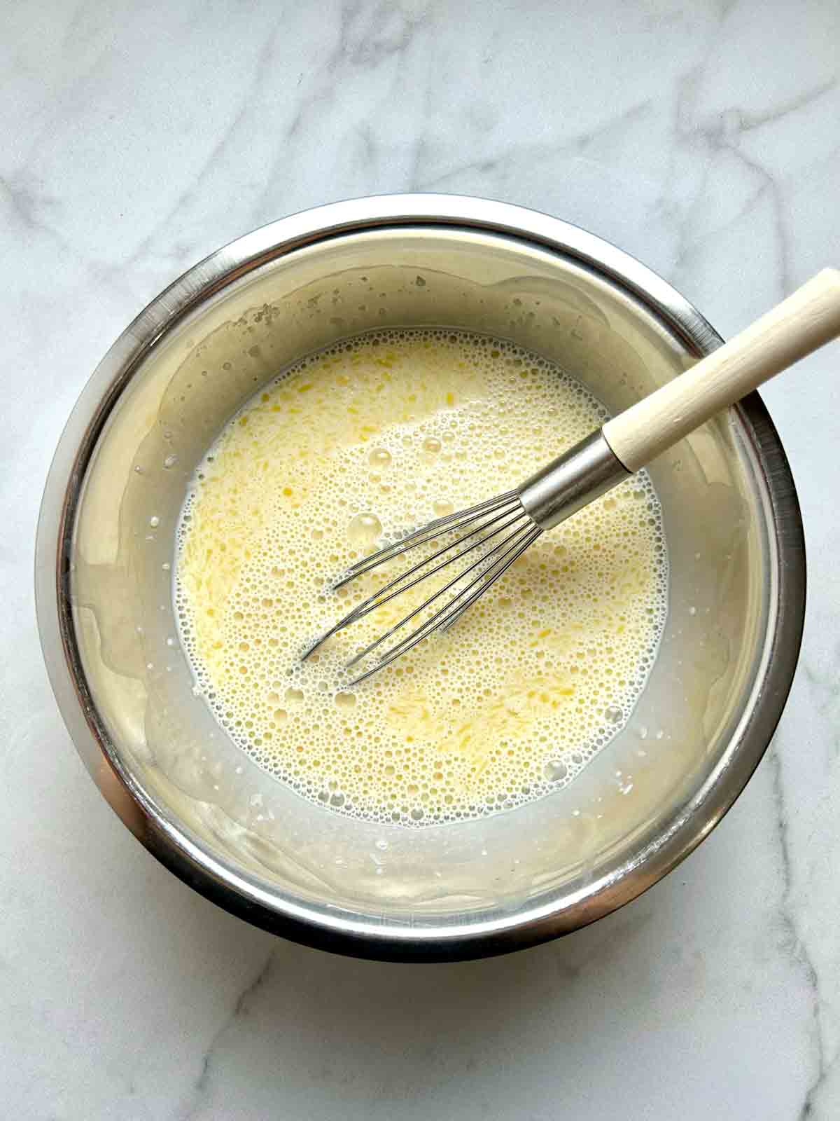wet ingredients being whisked together in bowl.
