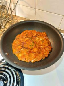 second side of kimchi pancake being pan-fried.