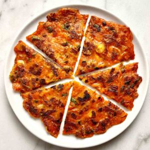 kimchi pancake cut into six slices on plate.