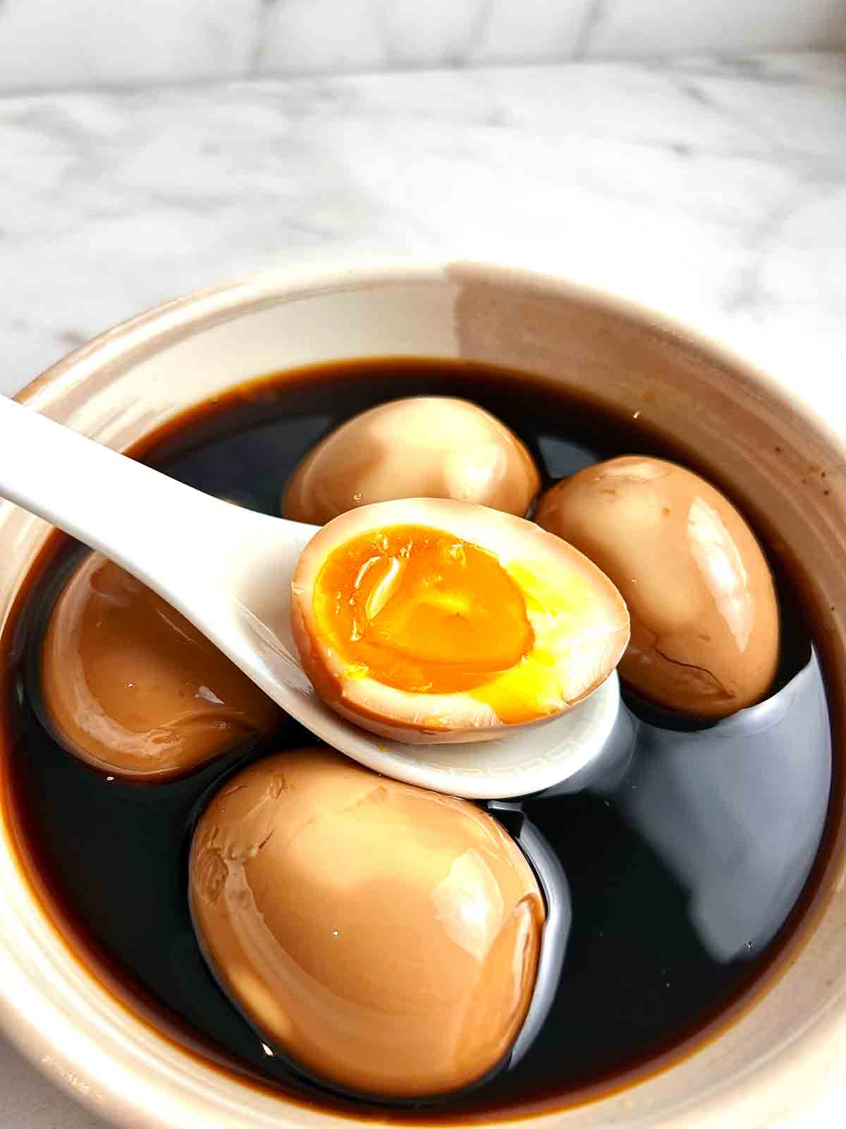 spoon lifting half-open ramen egg from bowl.