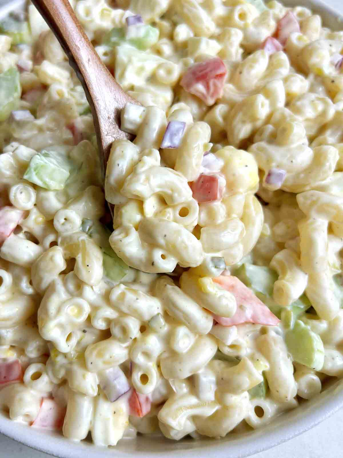 spoon lifting macaroni salad from bowl.