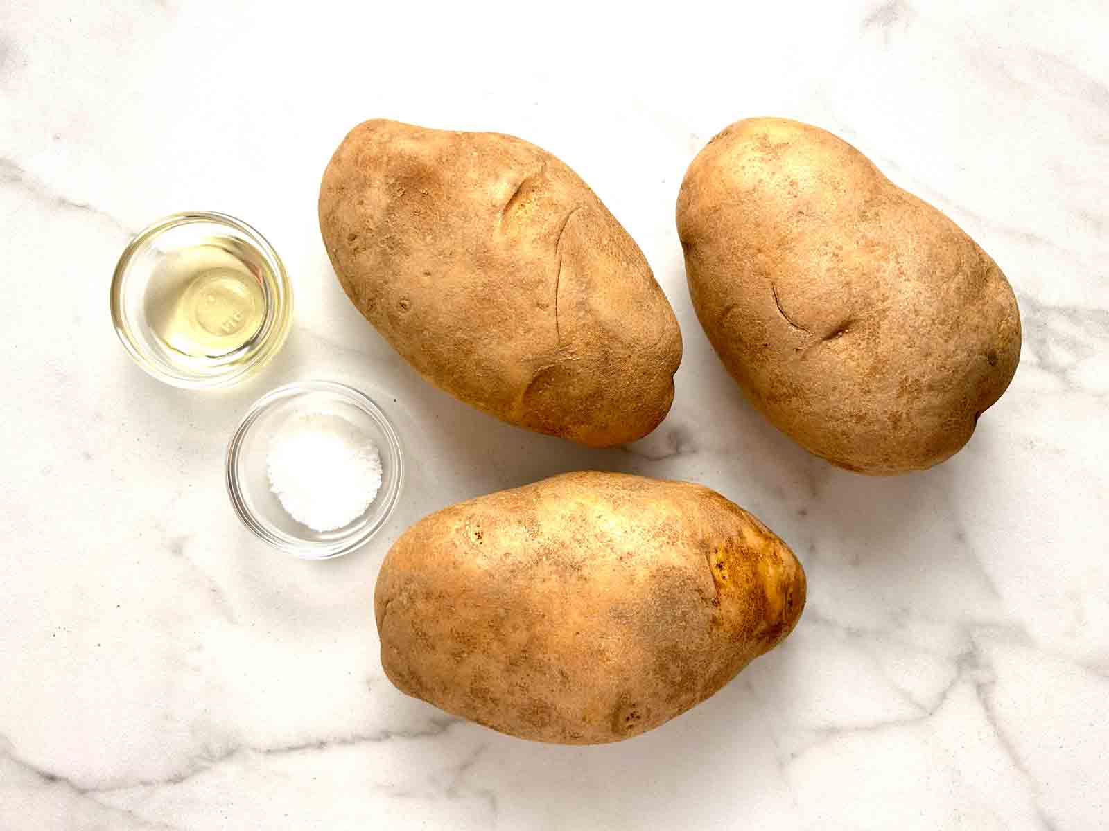 3 russet potatoes, bowl of oil, and bowl of salt.