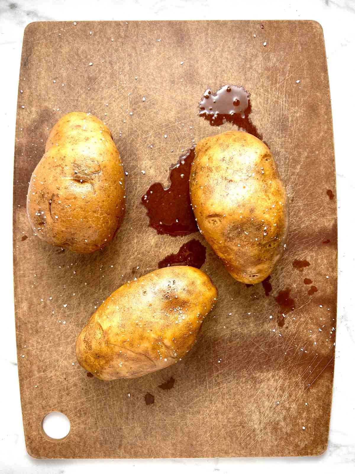 potatoes being rubbed with salt and oil.