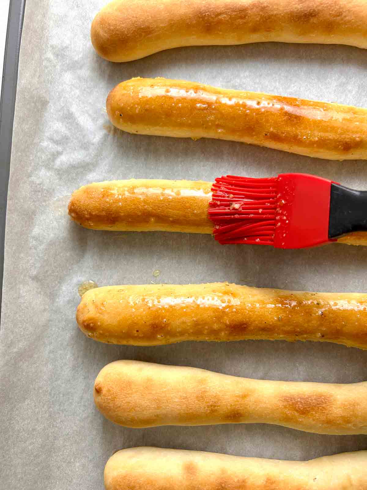 brushing garlic butter on breadsticks
