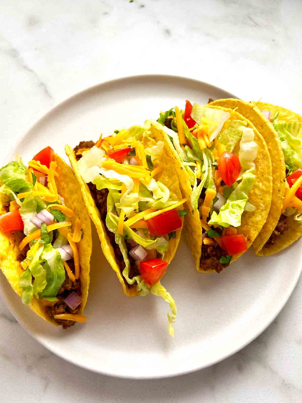 plate of homemade tacos in crunchy shell.