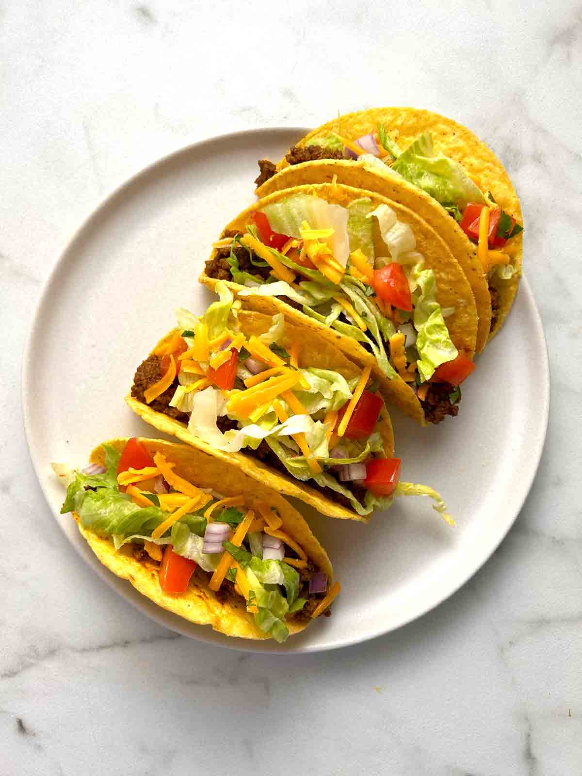 plate of homemade tacos in crunchy shell.