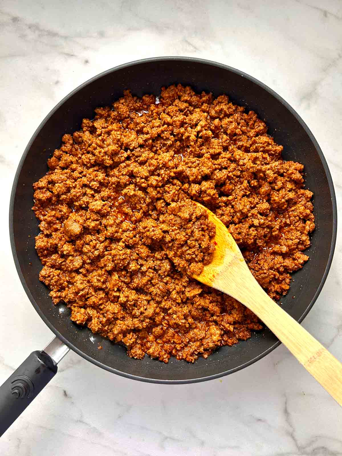 overhead shot of ground beef mixed with seasoning in pan.