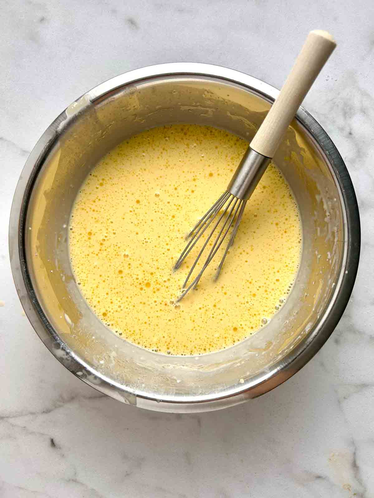 wet ingredients being whisked in bowl.