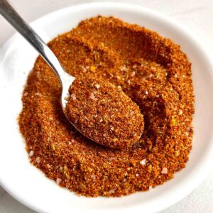 spoon lifting taco seasoning from small dish.