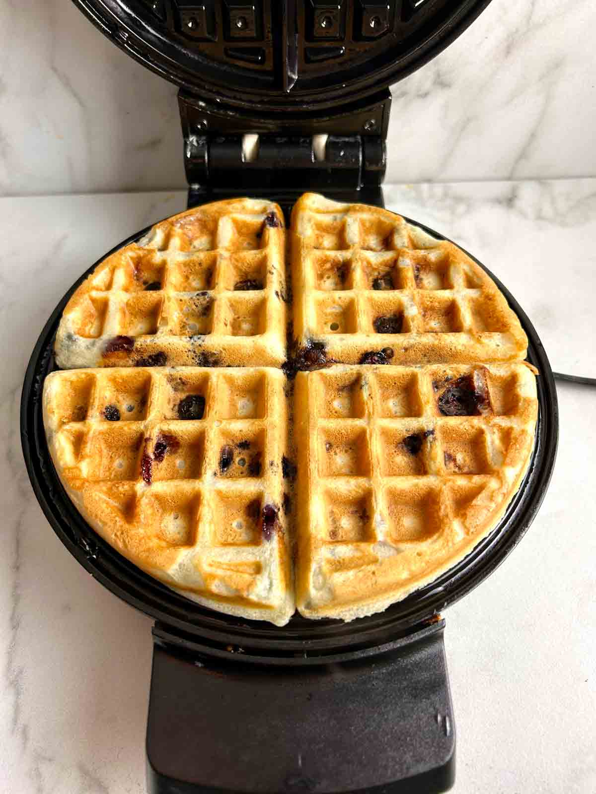 golden brown waffles in waffle iron.