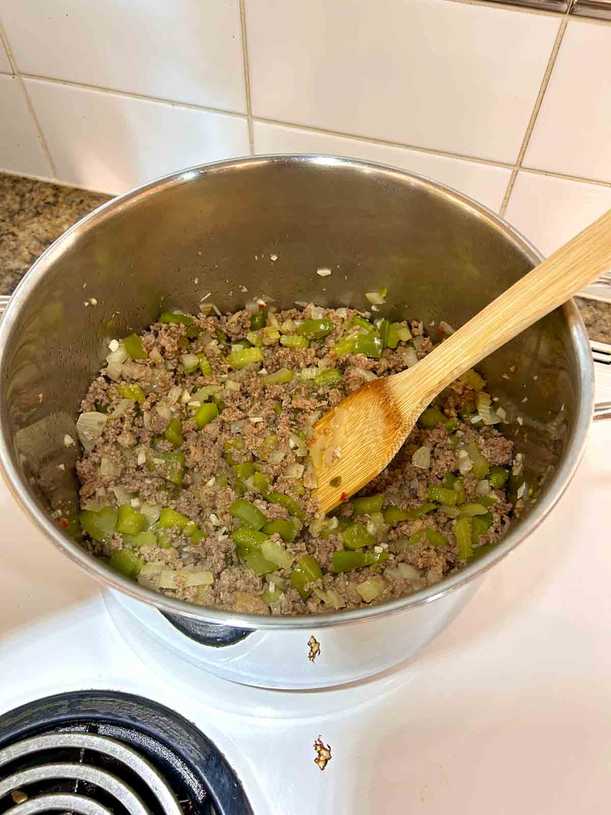 ground beef, Italian sausages, and vegetables cooked in pot.