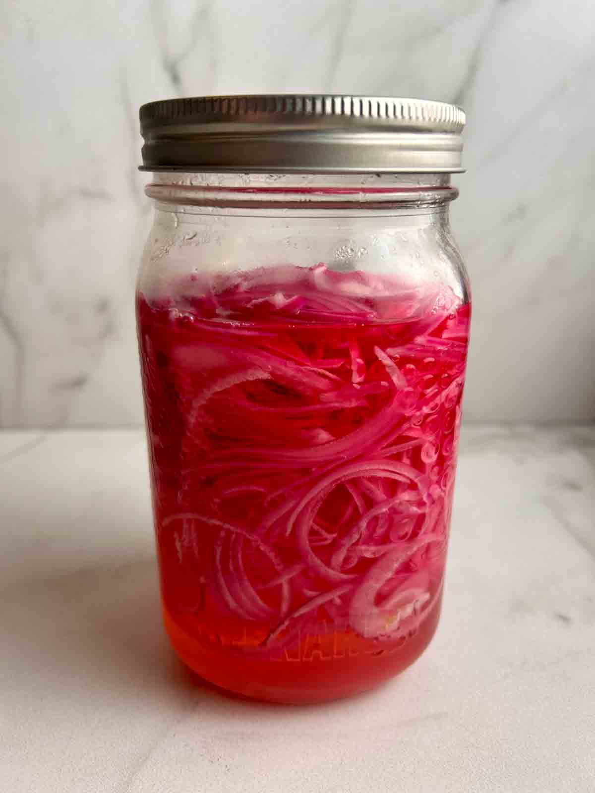 red onions after pickling for a few hours; color of brine is noticeably red.