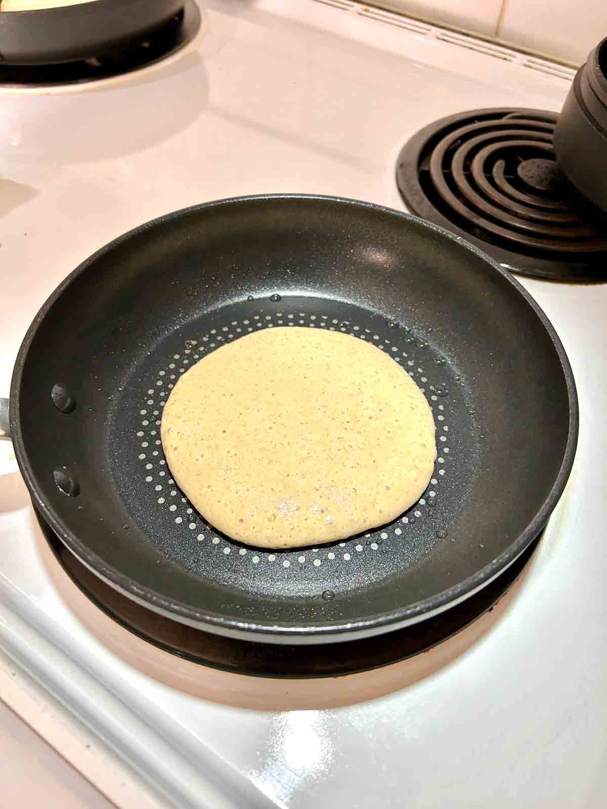 first side of pancake being cooked in skillet.