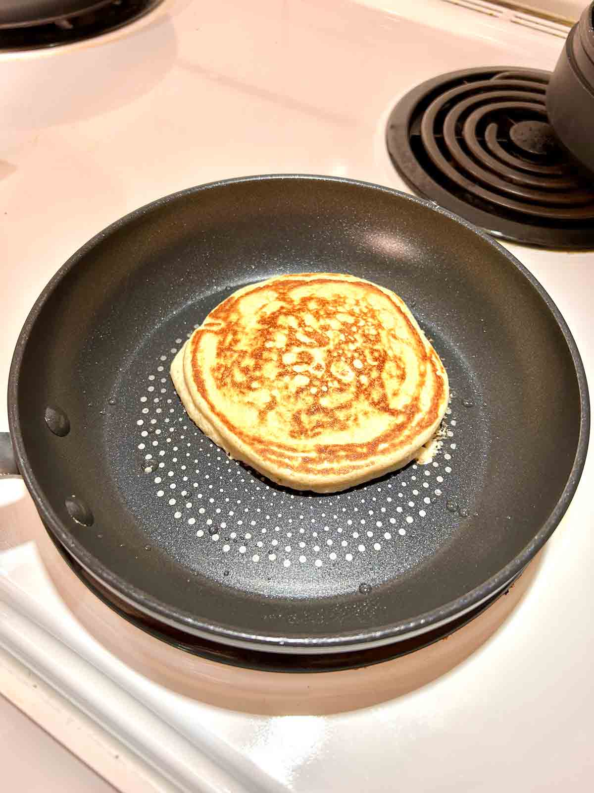 second side of pancake being cooked in skillet.