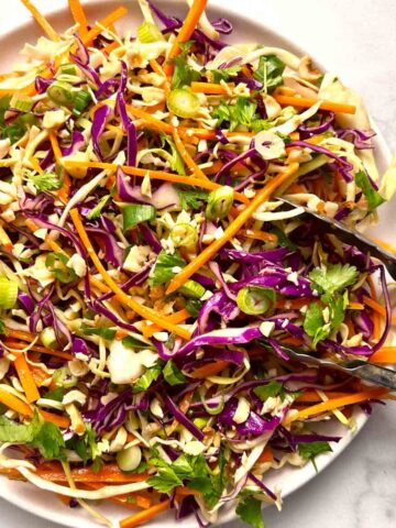 plate of Asian coleslaw with tongs.