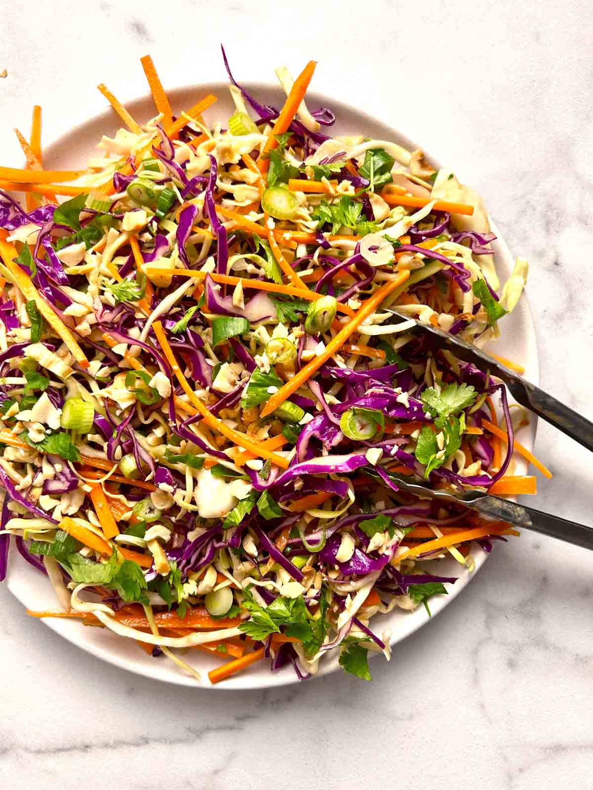 plate of Asian coleslaw with tongs.