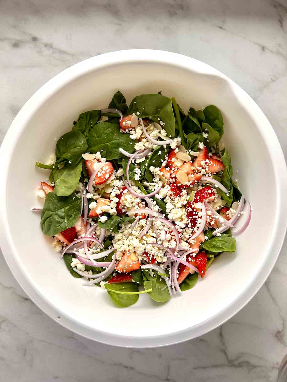 salad ingredients added to large bowl.