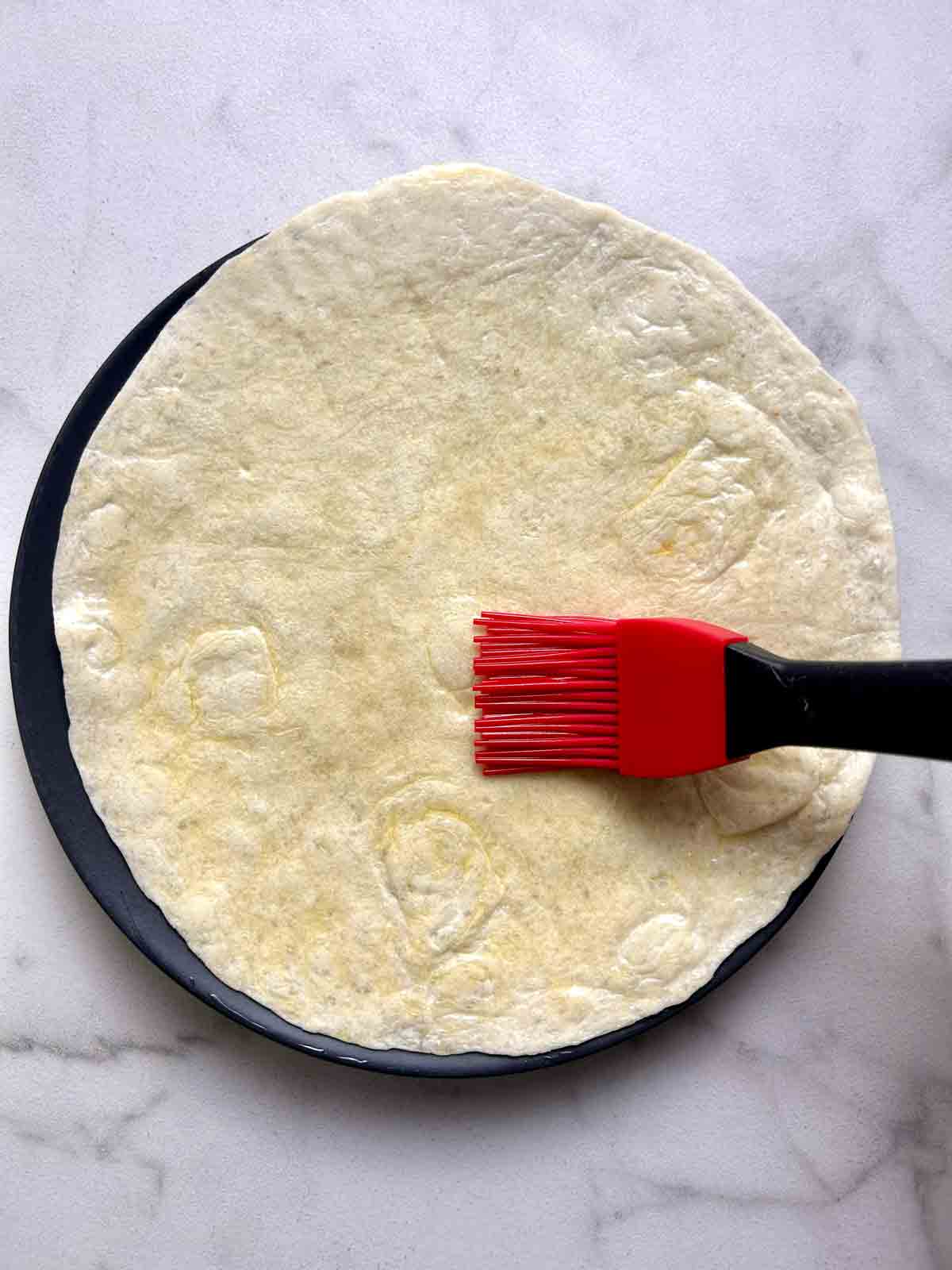 brushing olive oil onto tortilla.