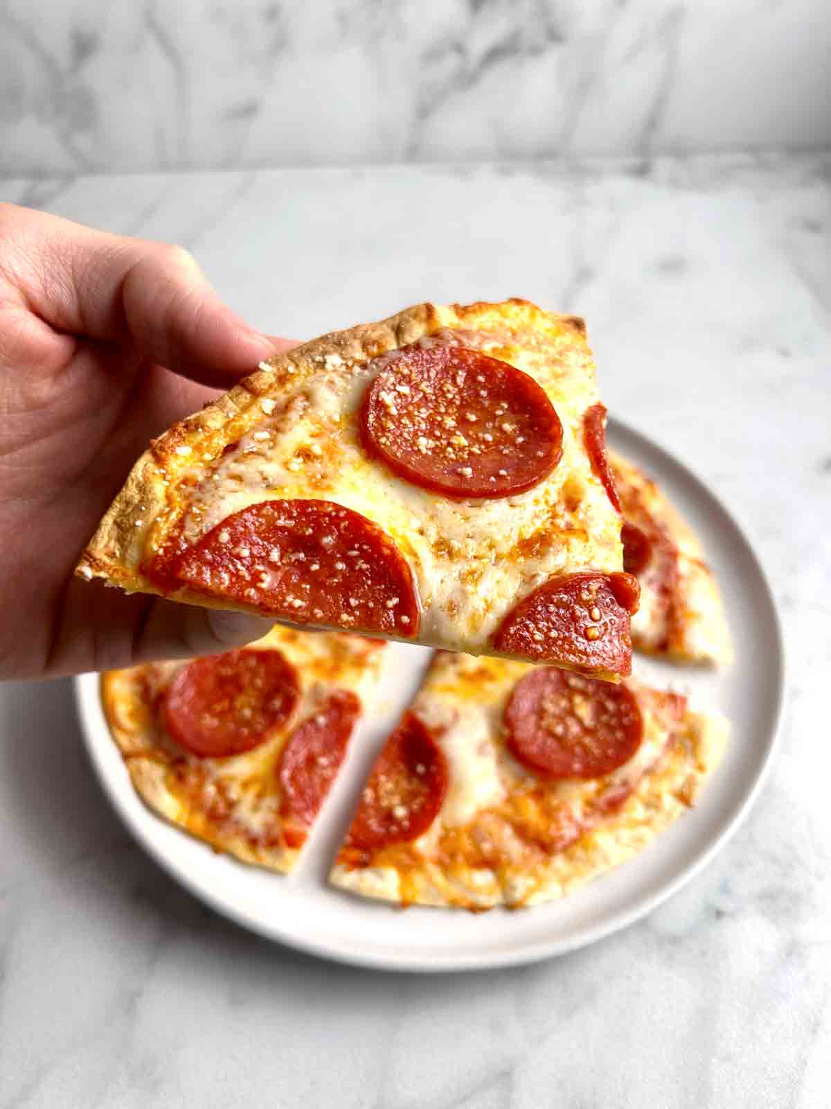 hand holding slice of tortilla pizza.