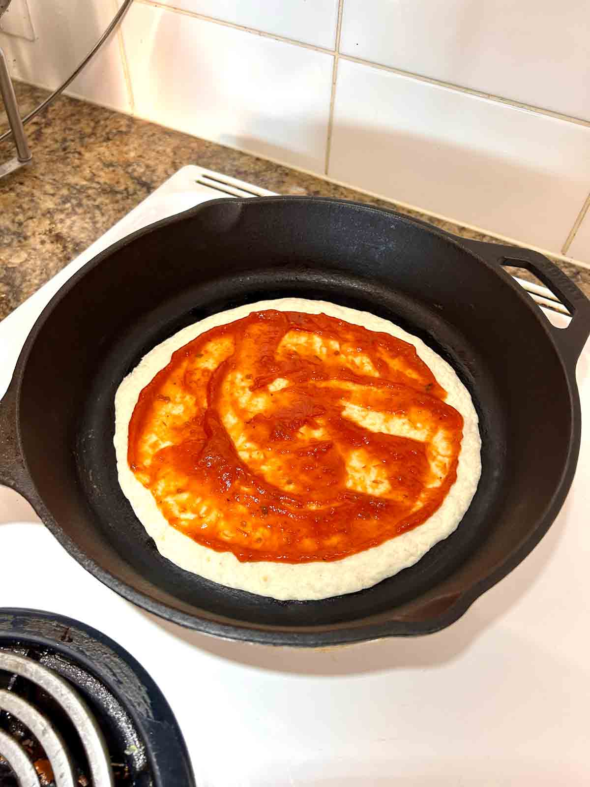 sauce being spread on tortilla.