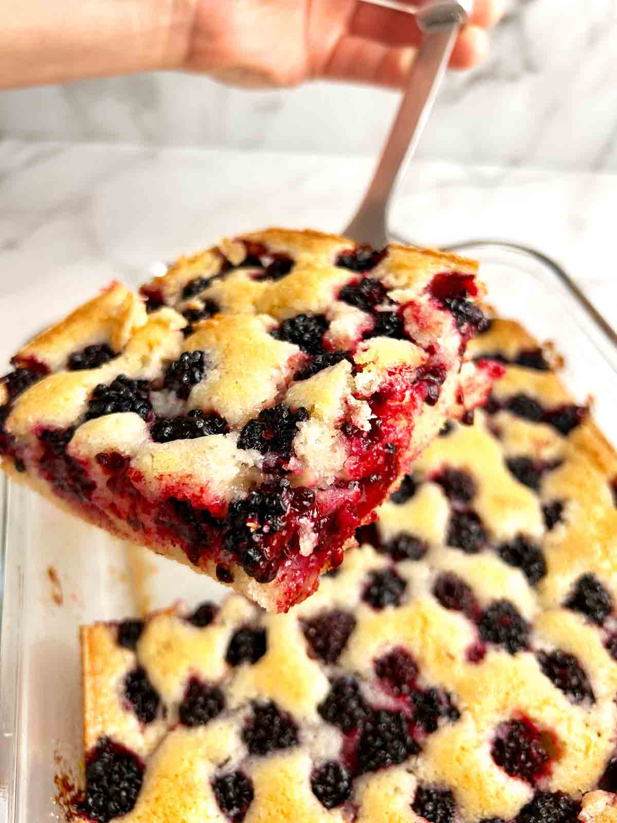 spatula lifting slice of cobbler from baking dish.