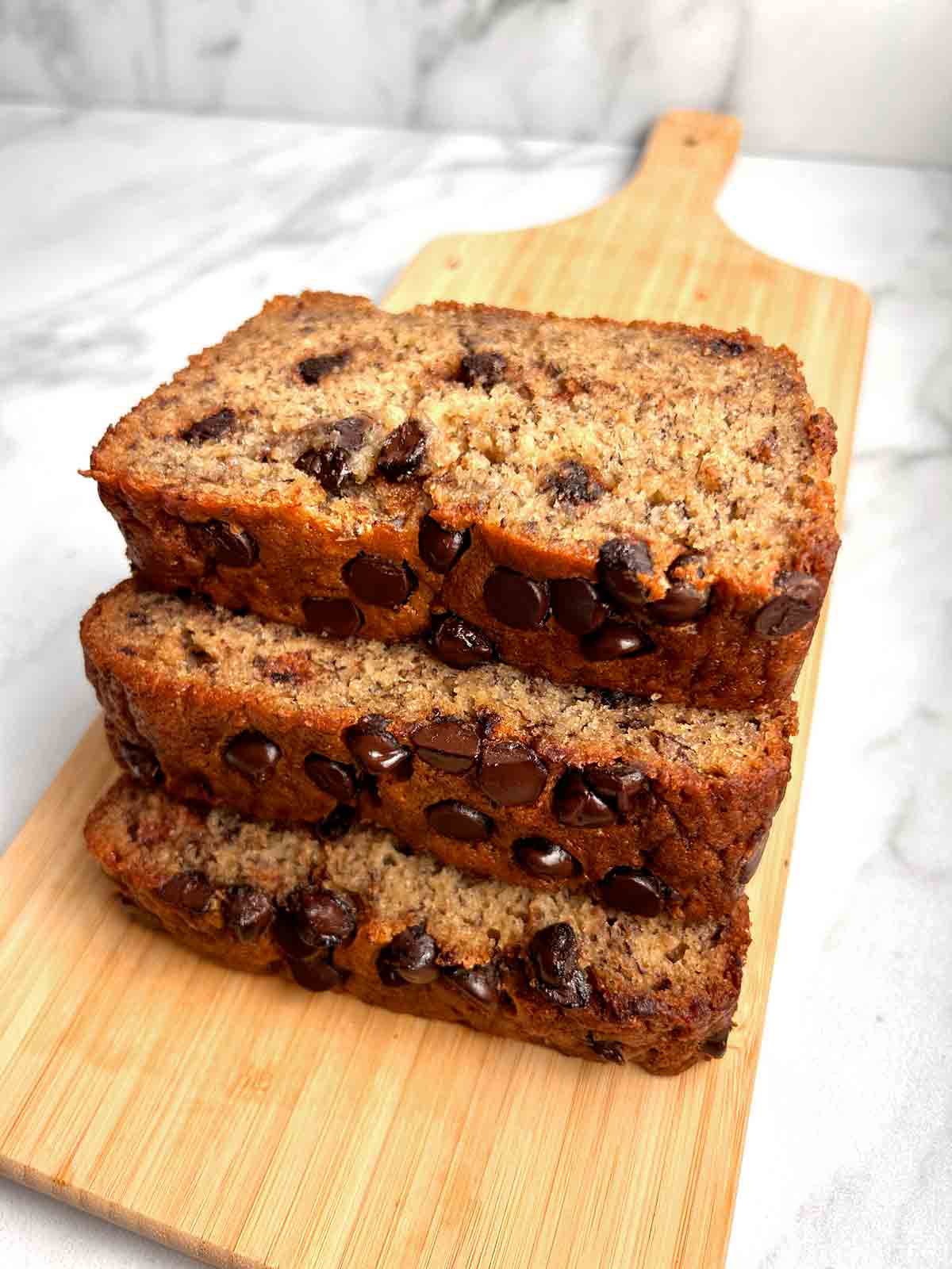 three slices of banana bread on wooden board.
