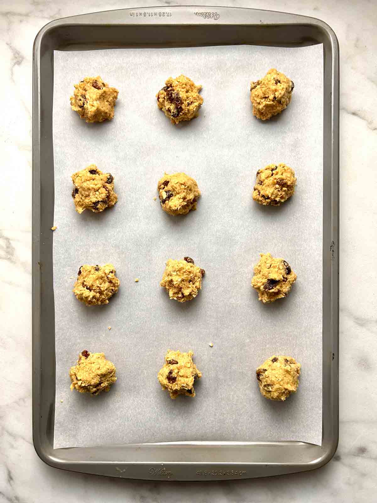 cookie dough shaped into balls on parchment-lined baking sheet.