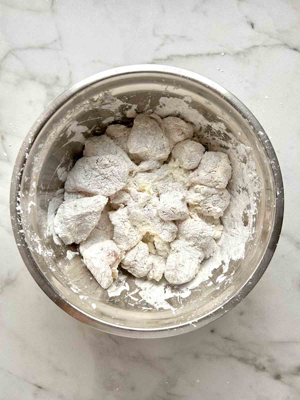chicken coated with cornstarch in bowl.