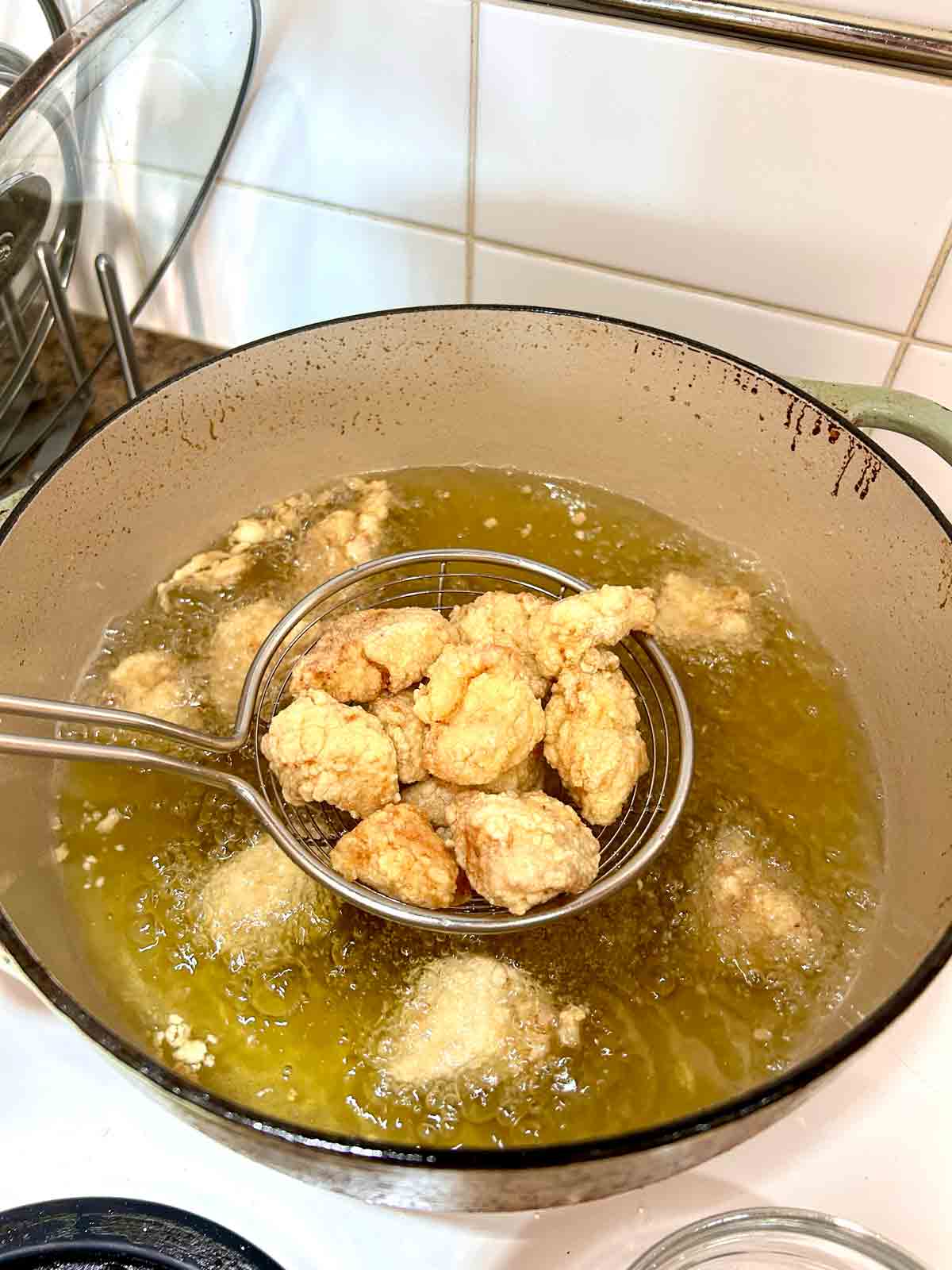fried chicken being lifted our of hot oil.