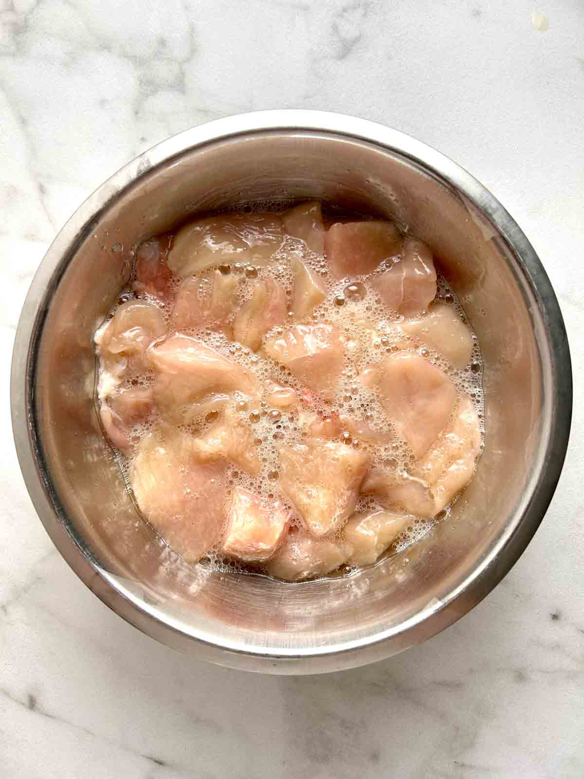 chicken being marinated in bowl.