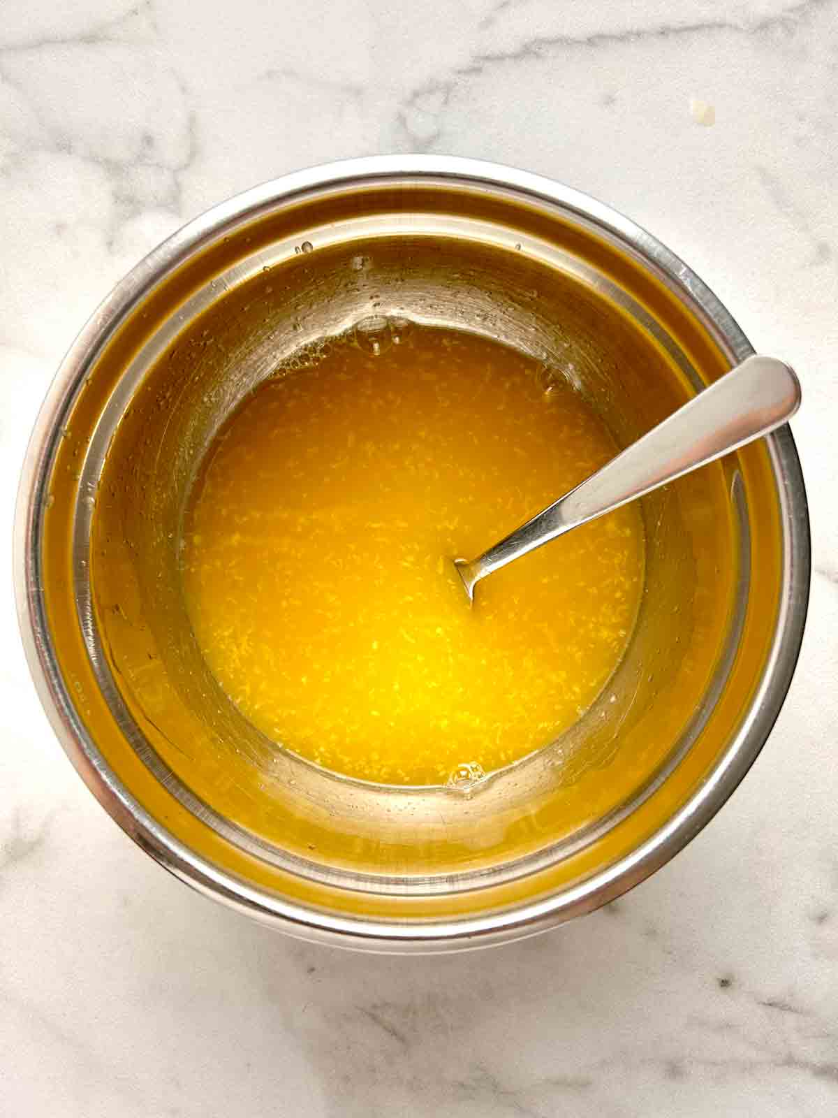 orange sauce being mixed in bowl.