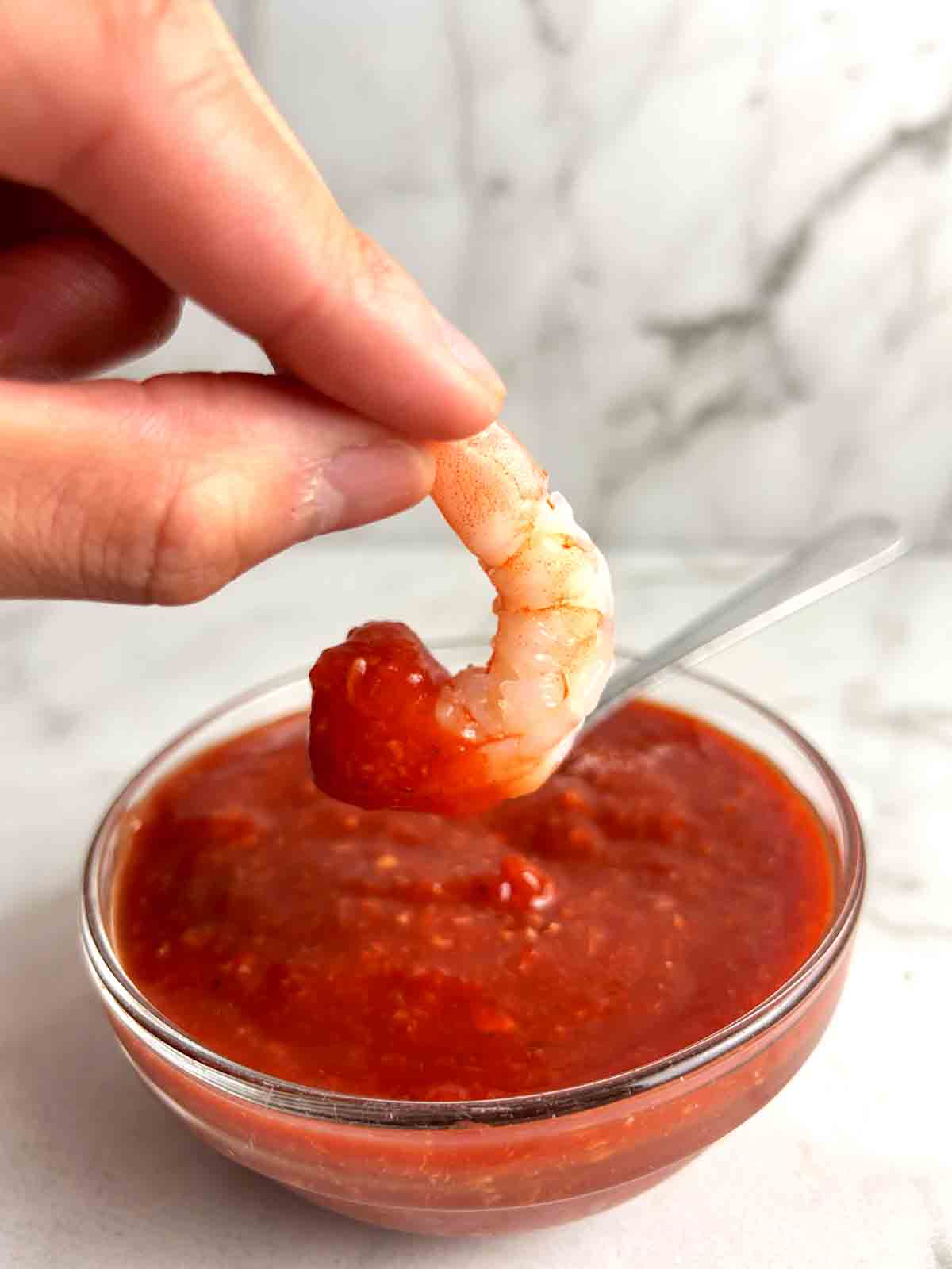 shrimp being dipped into cocktail sauce.