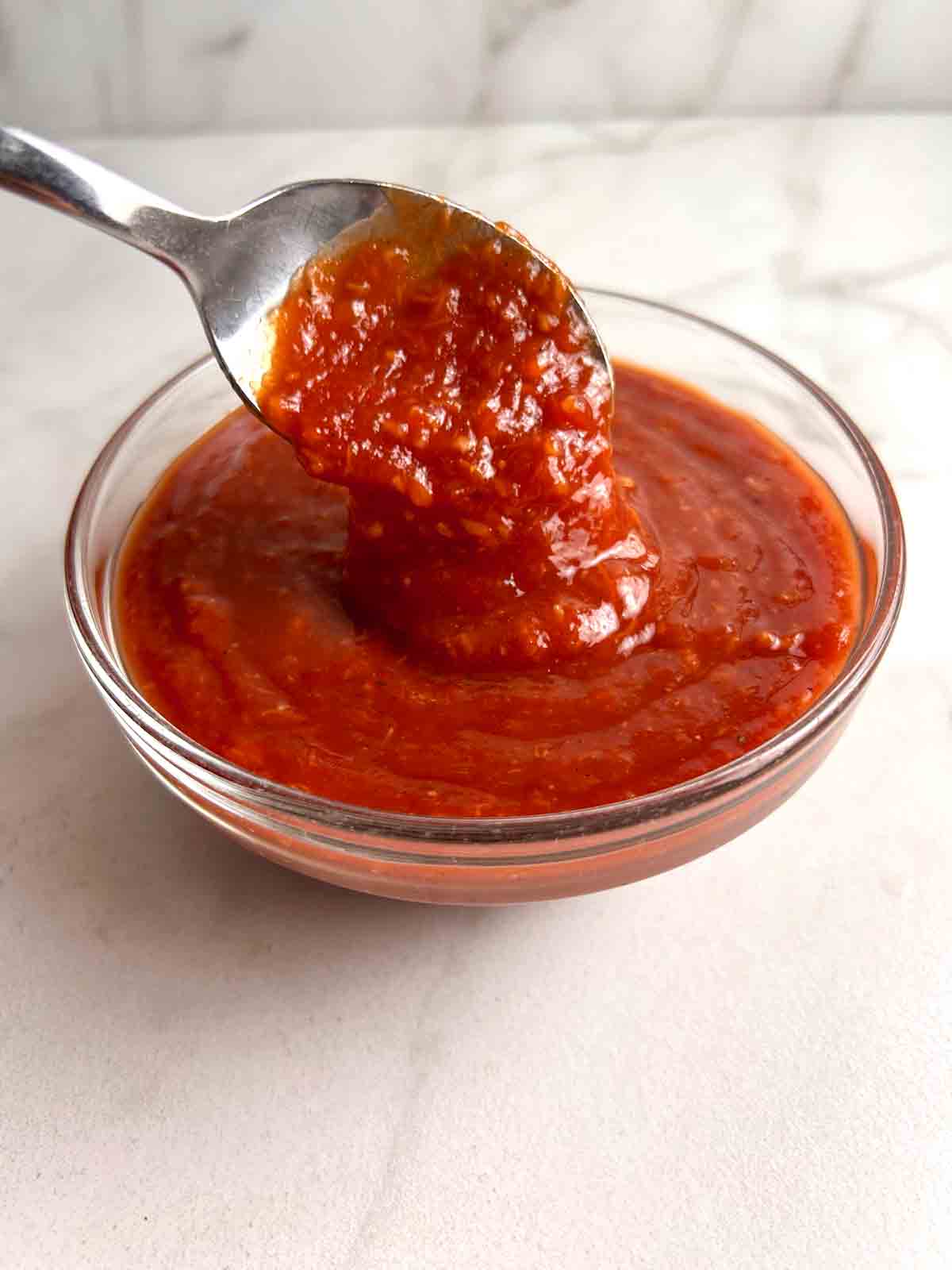 spoon lifting cocktail sauce from bowl.