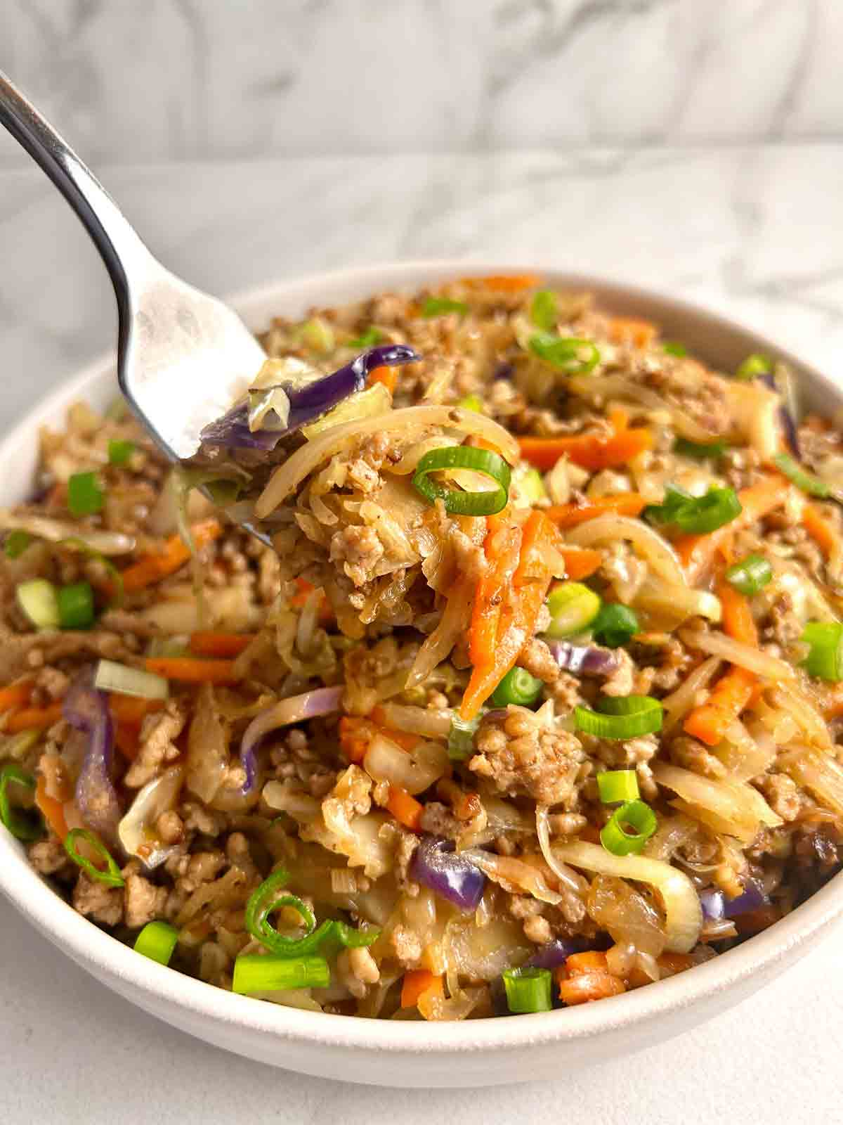 fork lifting egg roll in a bowl.