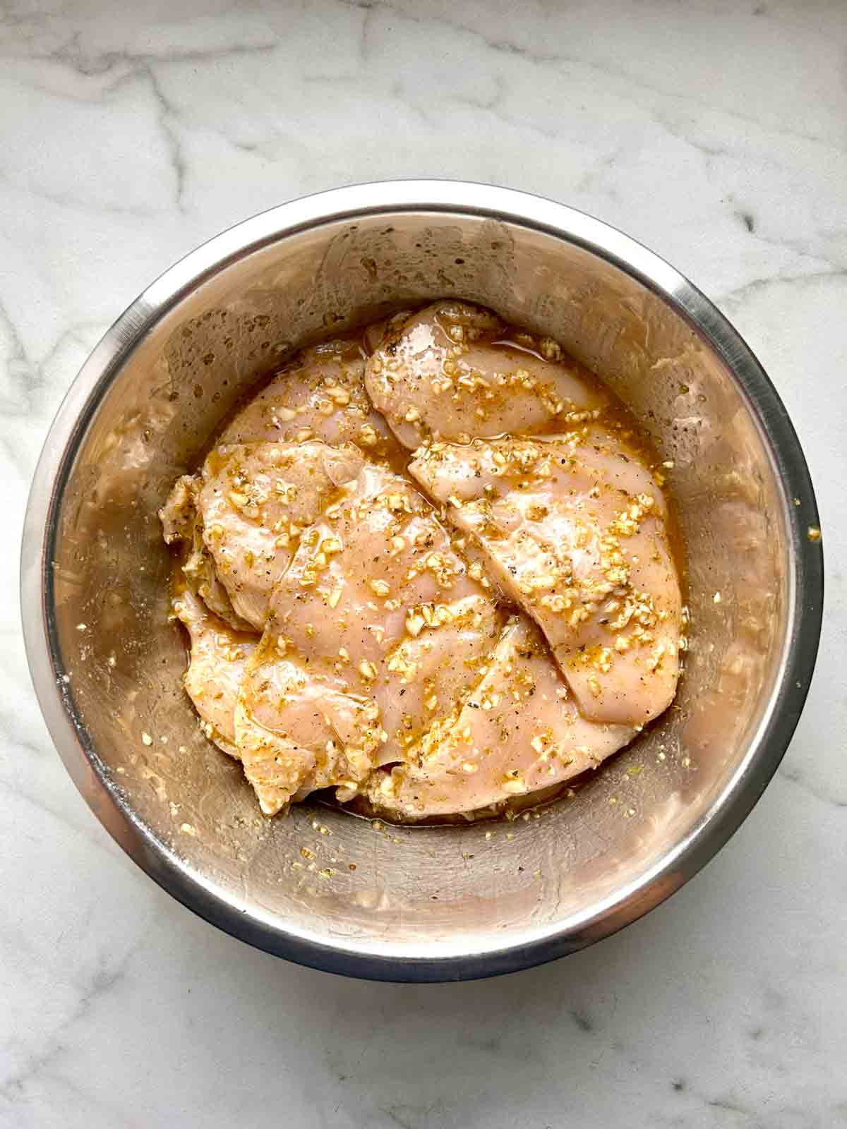chicken breasts marinating in bowl.