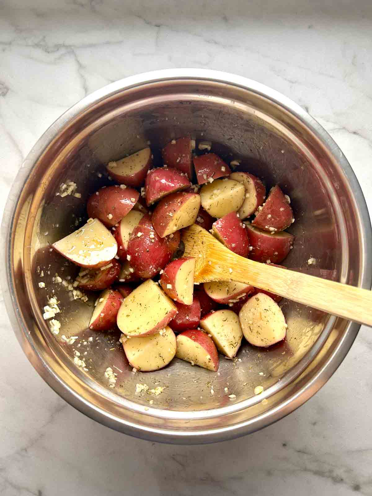 potatoes tossed with seasonings in bowl.