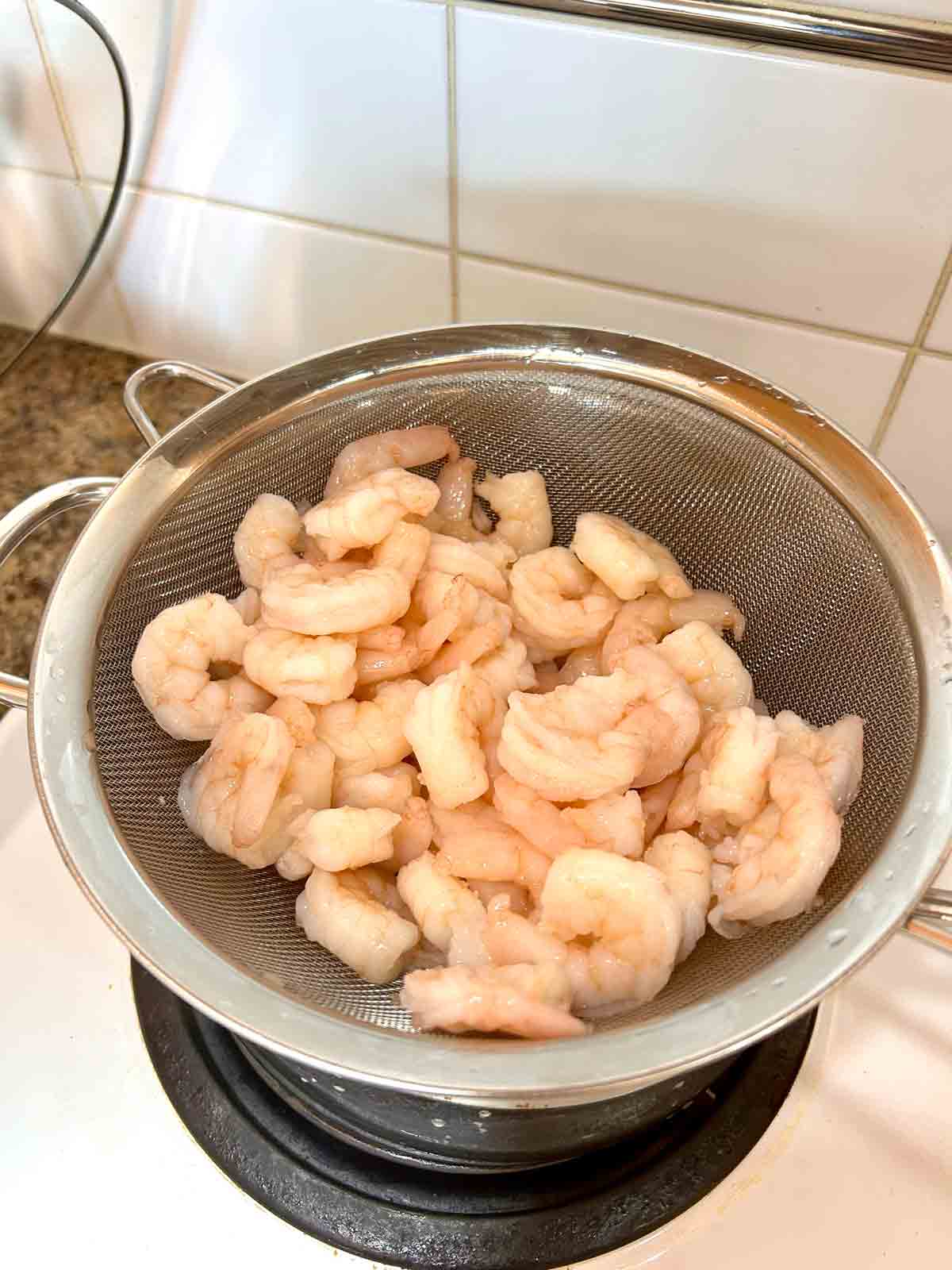 cooked shrimp draining in strainer.