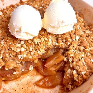 apple crisp in baking dish with two scoops of ice cream on top.