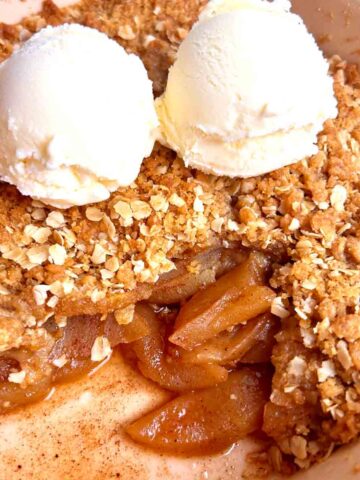 apple crisp in baking dish with two scoops of ice cream on top.