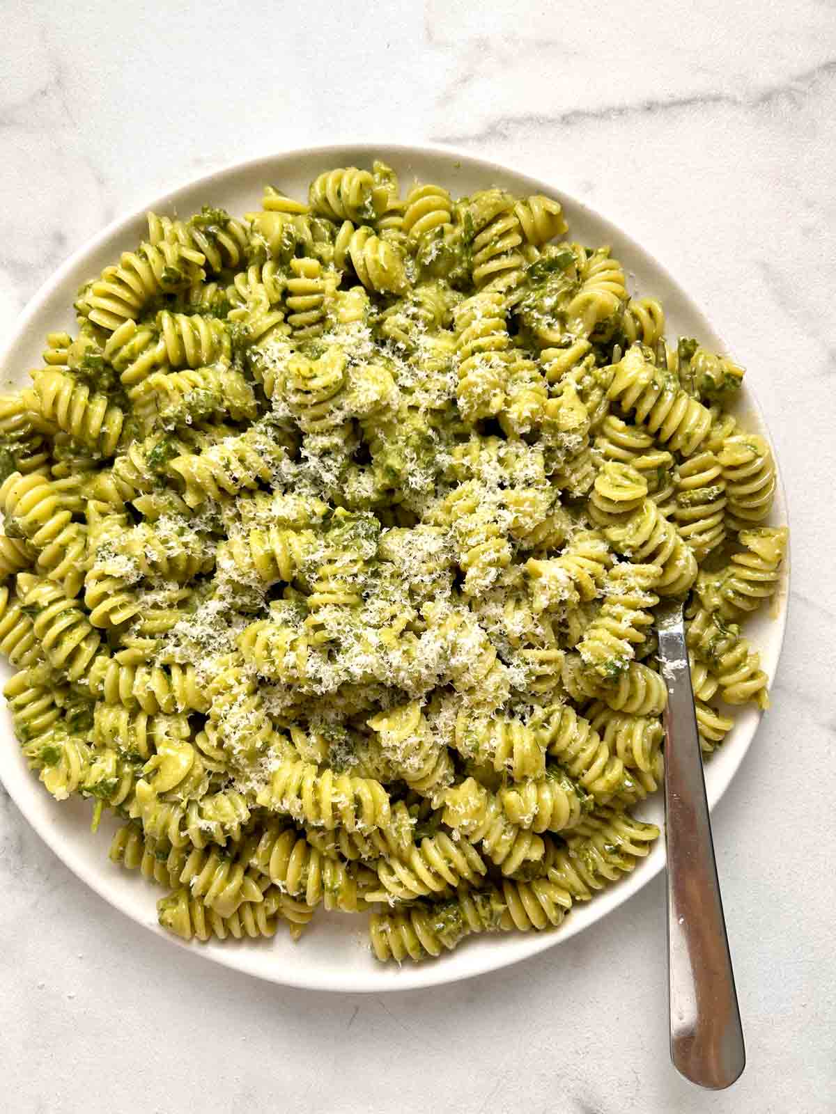 plate of pesto pasta with extra Parmesan cheese grated on top.